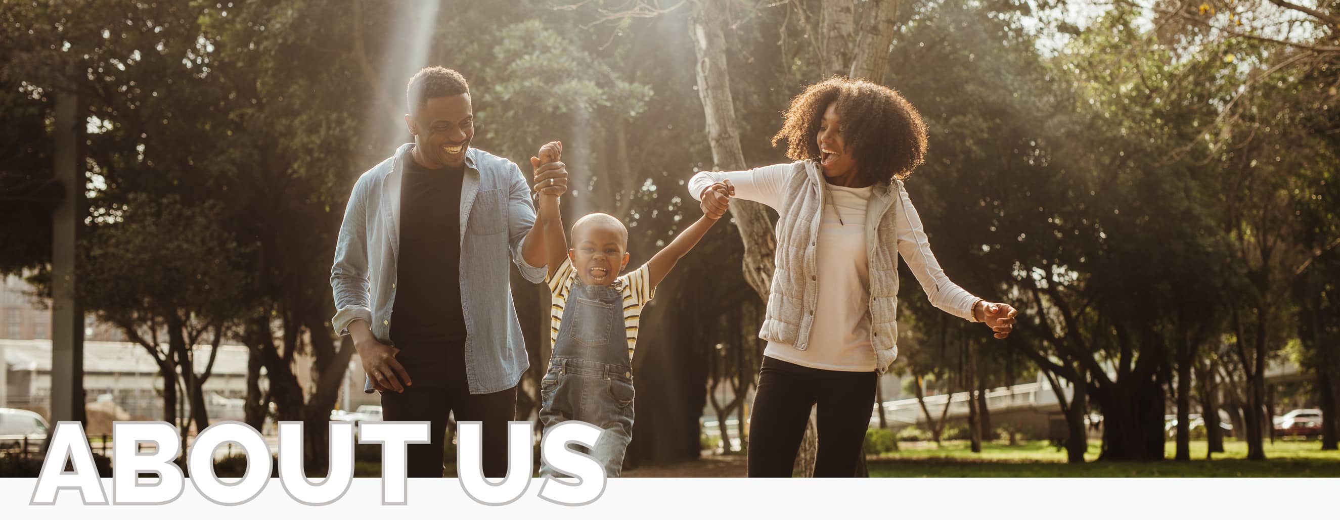 A young African American family, consisting of a young daughter, mother and father, outside laughing and playing together. The photo includes the words "About Us" in franklin tn