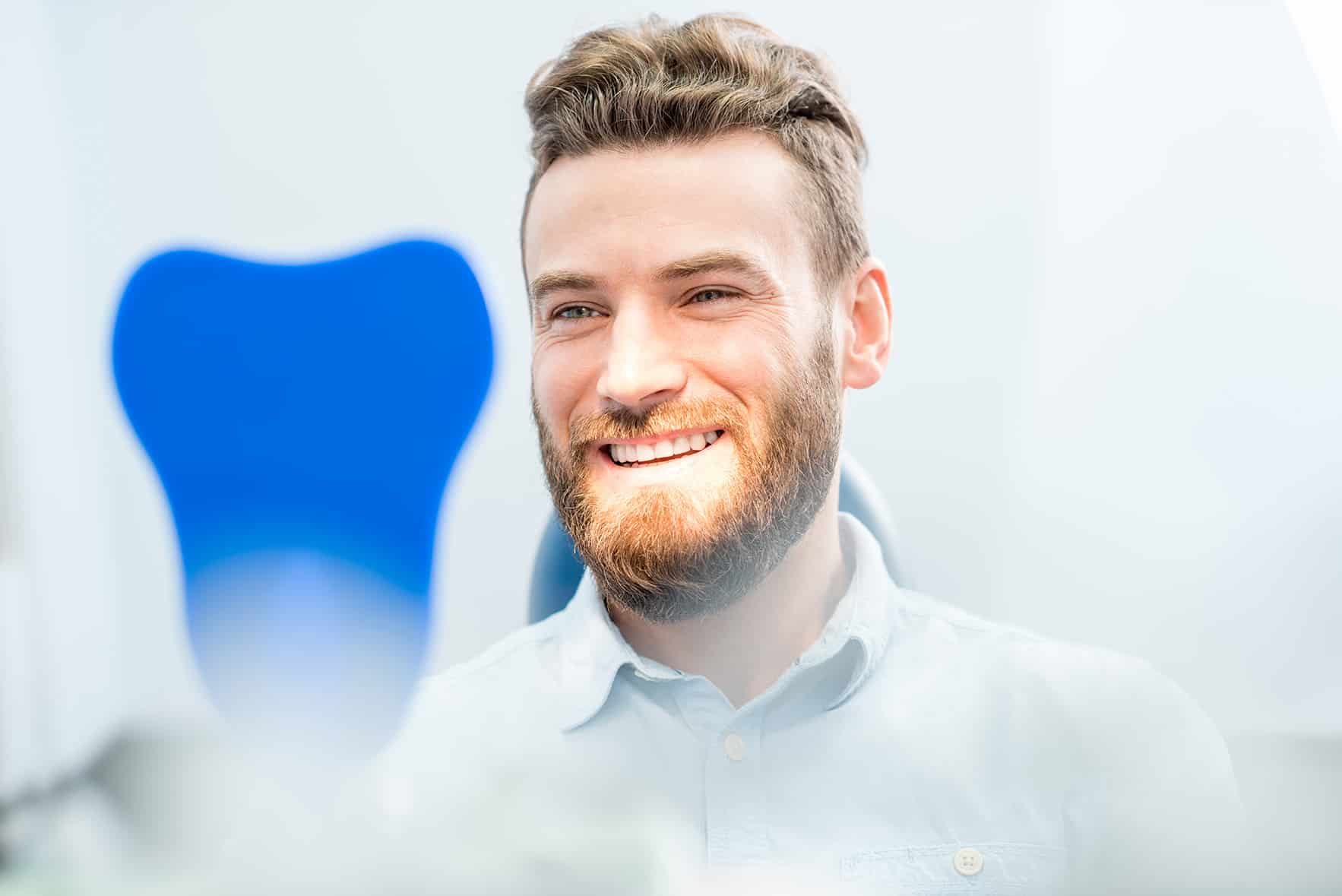 man looking in a mirror after teeth whitening appointment at kelly family dentistry