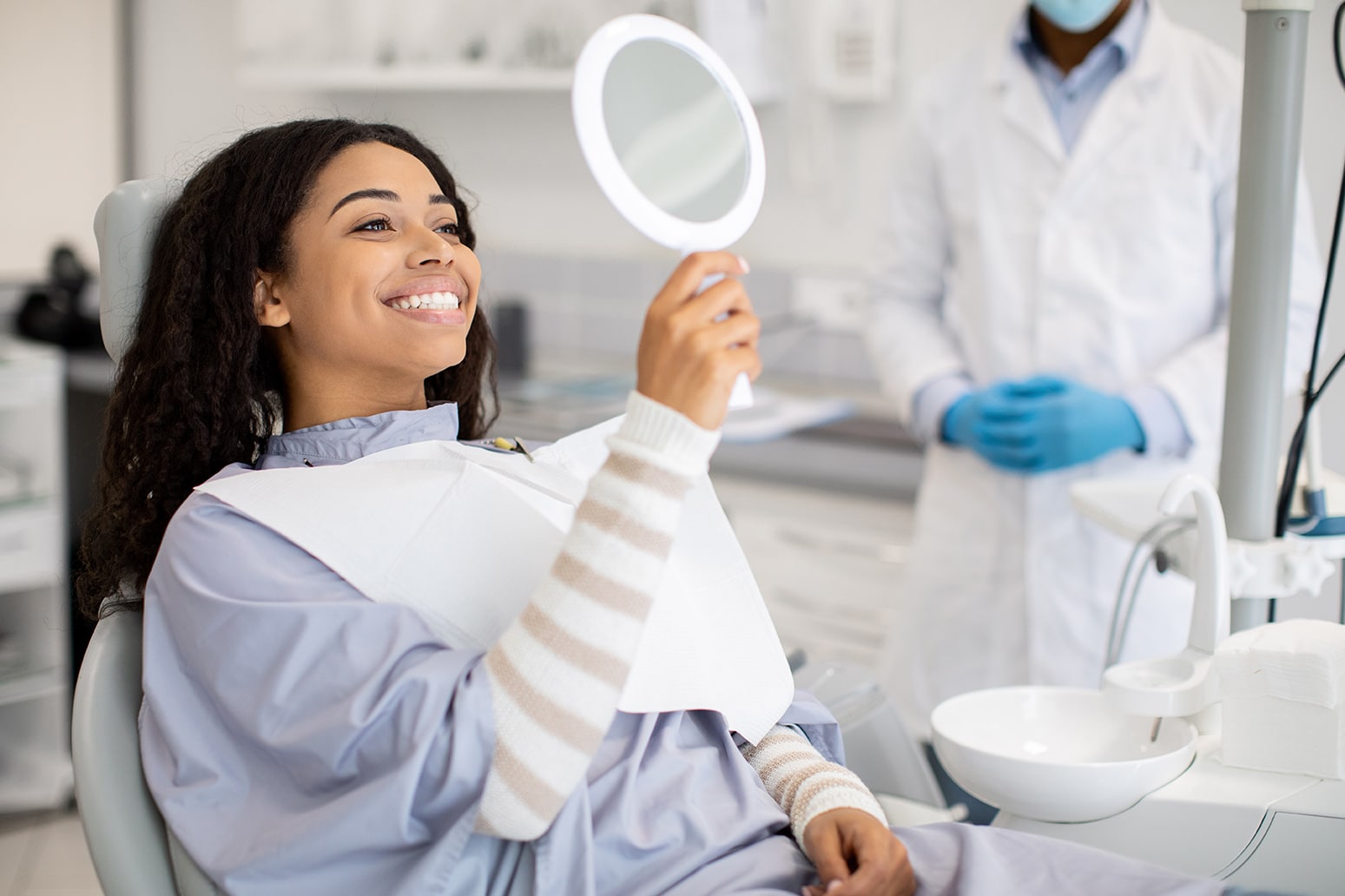 woman looking into a mirror during an emergency dental appointment at kelly family dentistry