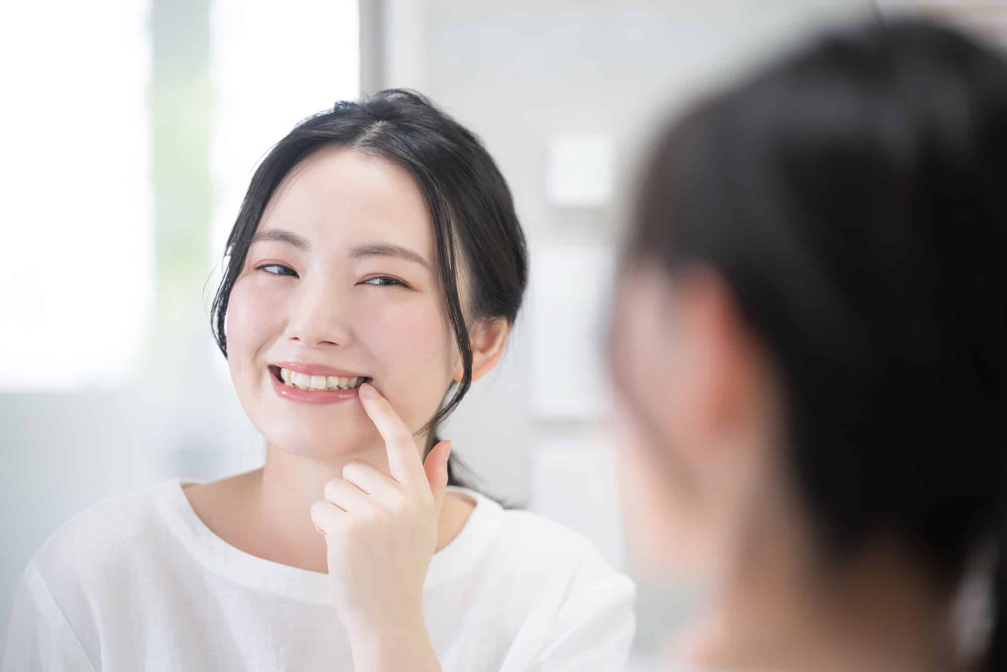 woman pointing to her teeth during cosmetic dental appointment at kelly family dentistry